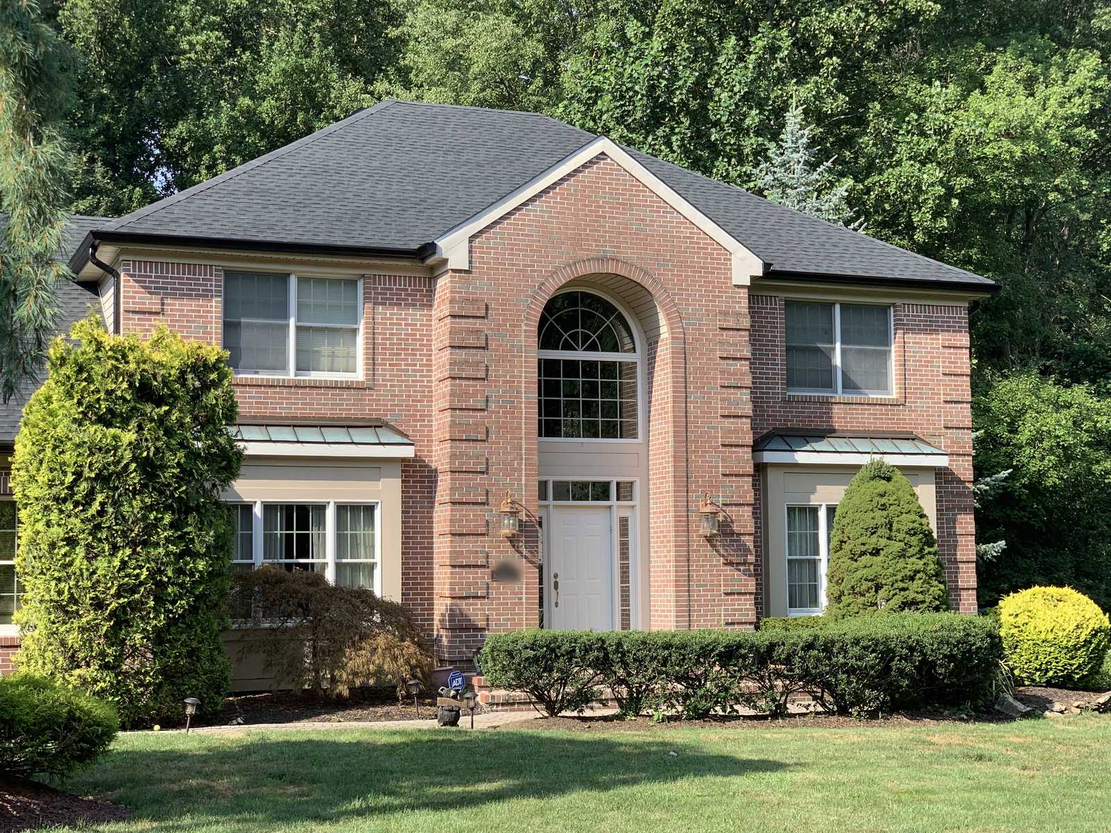 Brick-front colonial house with a charcoal architectural shingle hip roof